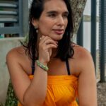 A thoughtful woman in a yellow dress sits outdoors, offering a serene summer portrait.